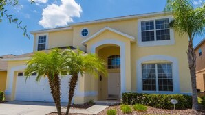 A two-story house with a garage, a front porch, and a well-maintained lawn with palm trees. - 7 BDRM, Private Pool/HotTub, Heat Included, Games (Kissimmee)