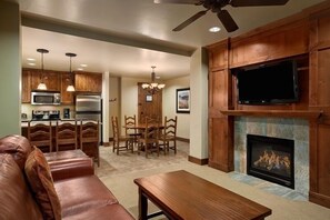 Cozy living room with a fireplace, television, and dining area, featuring a kitchen with modern appliances.