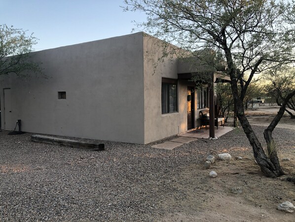 A modern building with a concrete exterior, a small porch, and a gravel driveway.