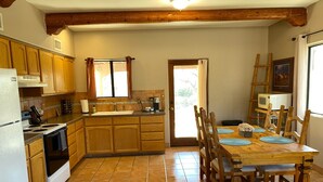 A kitchen with wooden cabinets, a tiled floor, a dining table with chairs, and a refrigerator. - Ranch Casita: views, views, views! (Tucson)