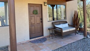 A wooden door with a wreath, a wicker bench with cushions, and a small table. - Ranch Casita: views, views, views! (Tucson)