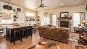 A spacious living area with a fireplace, a dining area, and a kitchen with bar stools. - Spacious in & outdoor Gastehaus.Great for enjoying the hill country.Walk to Main (Fredericksburg)