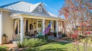 A house with a porch, a flag, and a garden. - Spacious in & outdoor Gastehaus.Great for enjoying the hill country.Walk to Main (Fredericksburg)