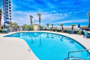 Relax by the pool surrounded by comfortable seating and a scenic ocean view.