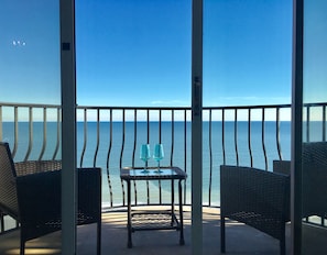 Enjoy the ocean view from this balcony with two comfortable chairs and a small table.