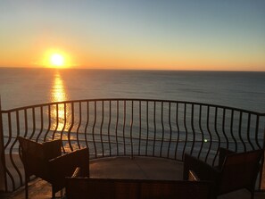 Enjoy breathtaking views of the water from this balcony with two comfortable chairs.