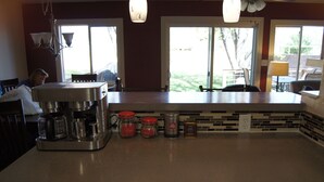 A kitchen with a coffee maker, jars of tea and sugar, and a tiled backsplash. - Remodeled in-town beauty with Mountain Views! Large, fully fenced back yard. (Kanab)