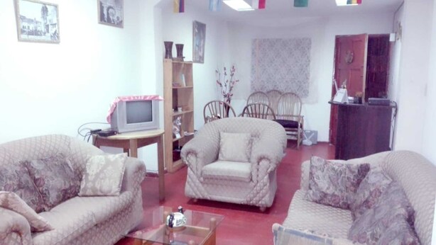 A living room with two sofas, a coffee table, a TV, and a bookshelf. - New Day House in Cusco (Centro Histórico)