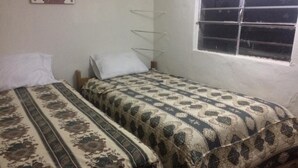 A small, simple room with two single beds, a window, and a plain wall. - New Day House in Cusco (Centro Histórico)