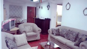 A living room with two sofas, a coffee table, a TV on a stand, and a door leading to another room. - New Day House in Cusco (Centro Histórico)