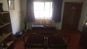 A room with a sofa set, a wooden cabinet, a bookshelf, and a window with curtains. - New Day House in Cusco (Centro Histórico)