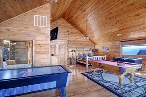 Un intérieur en bois avec une table de billard, un baby-foot et un canapé.