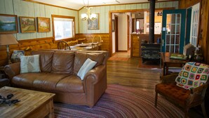 Ein gemütliches Wohnzimmer mit einer braunen Ledersofa, Holzwänden und einem Essbereich mit Tisch und Stühlen.