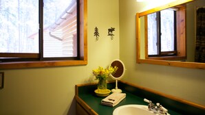 Ein Badezimmer mit Fenster, Spiegel, Waschbecken und Handtuch.