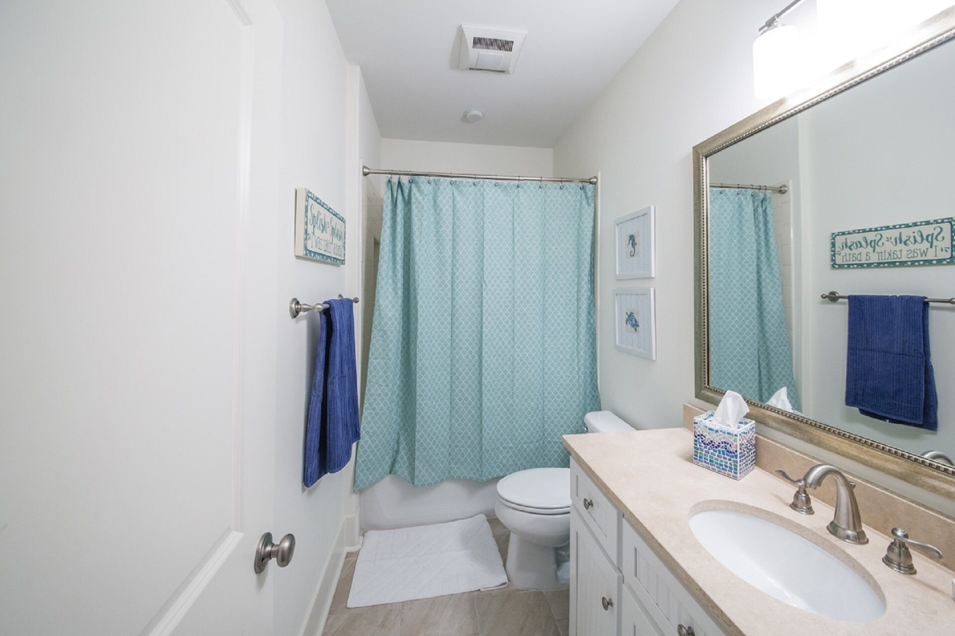 Un baño con inodoro, lavamanos y cortina de ducha.