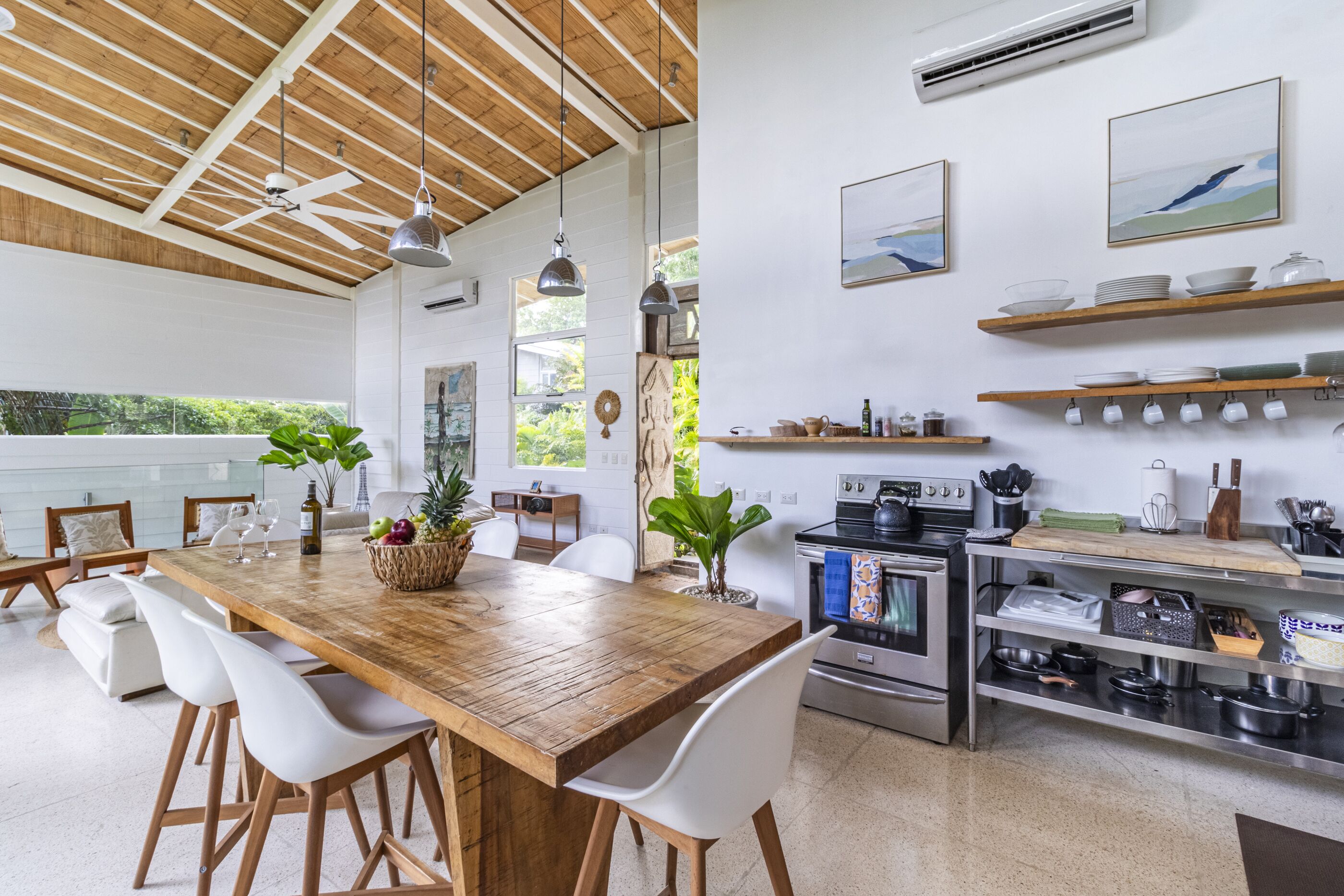 Een moderne keuken met houten aanrechtbladen, witte stoelen en roestvrijstalen apparatuur.