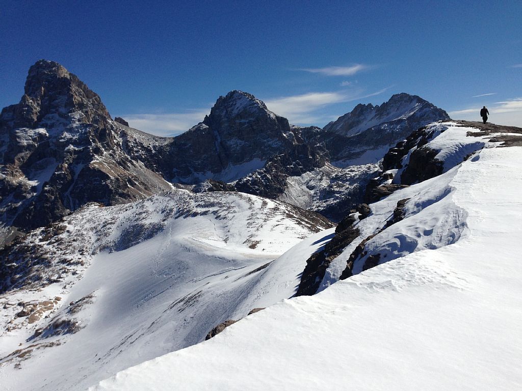 A snow-covered mountain landscape with rocky peaks and a clear sky.