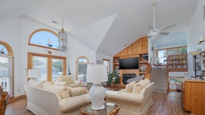 Un salón amplio con televisor grande, asientos cómodos, pisos de madera y chimenea.