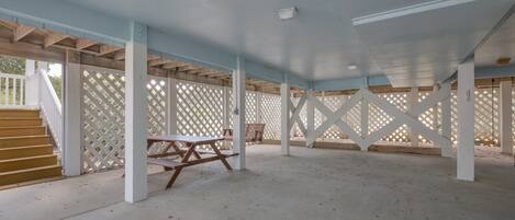 En åben patio med en trætrap, picnicborde og et espalier.