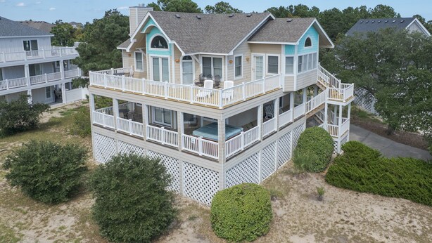 Una casa frente al mar de varios pisos, con balcón, terraza y escalera que lleva al piso superior.