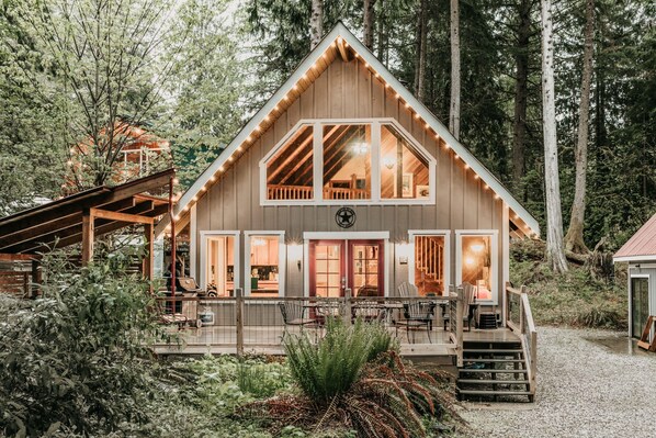 Escape to a serene forest retreat with a cozy cabin-style building featuring a gabled roof and large windows.