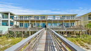 A wooden boardwalk leading to a beachfront hotel with multiple balconies and rooms. - Seagull-Gulf Front Home with Private Beach Crossover No Pets (Navarre)