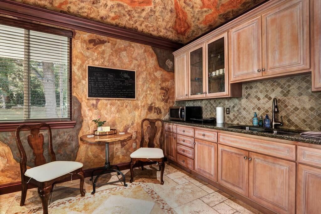 Une cuisine avec des meubles en bois, un plan de travail en granit et un tableau noir servant de menu.