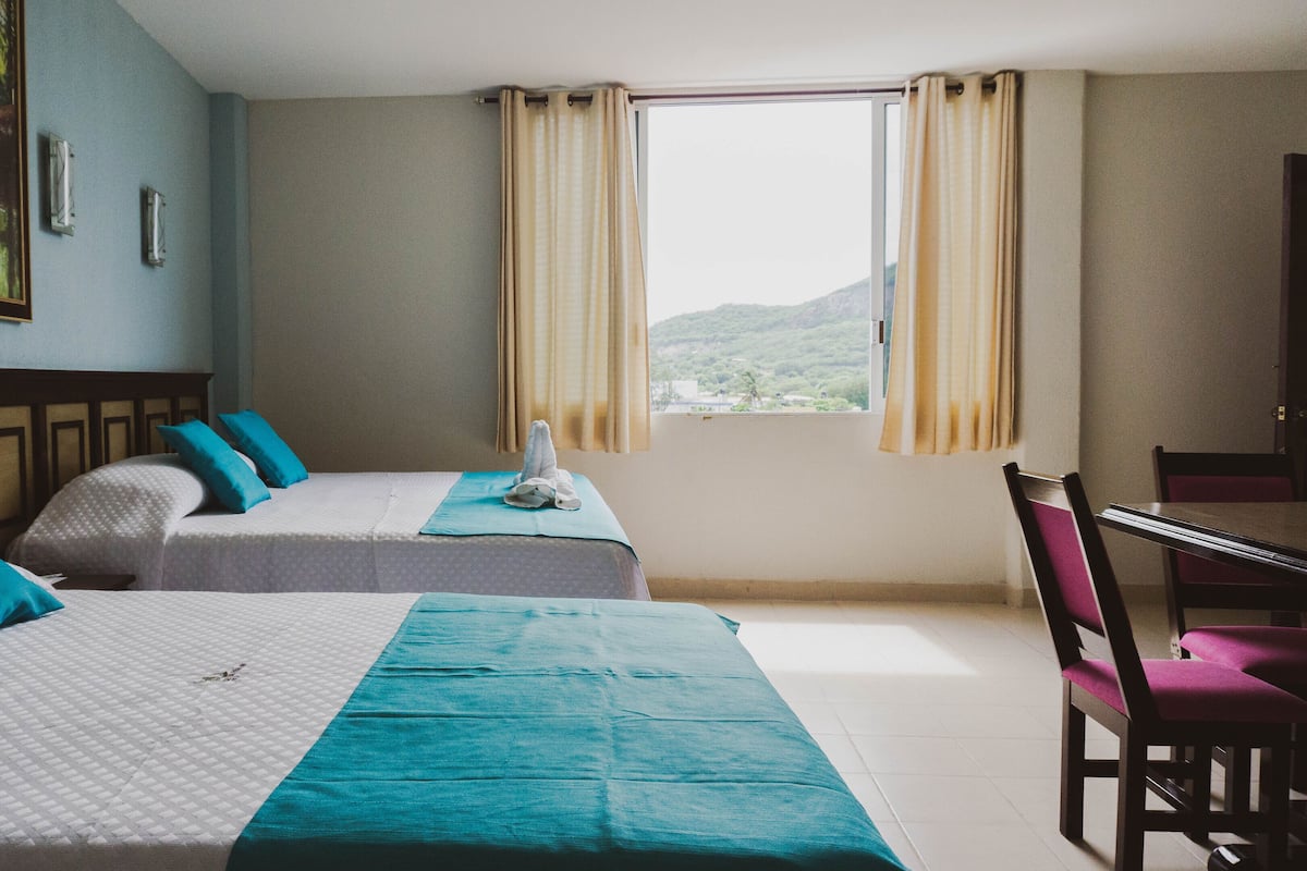 A hotel room with two beds, a desk, and a chair.