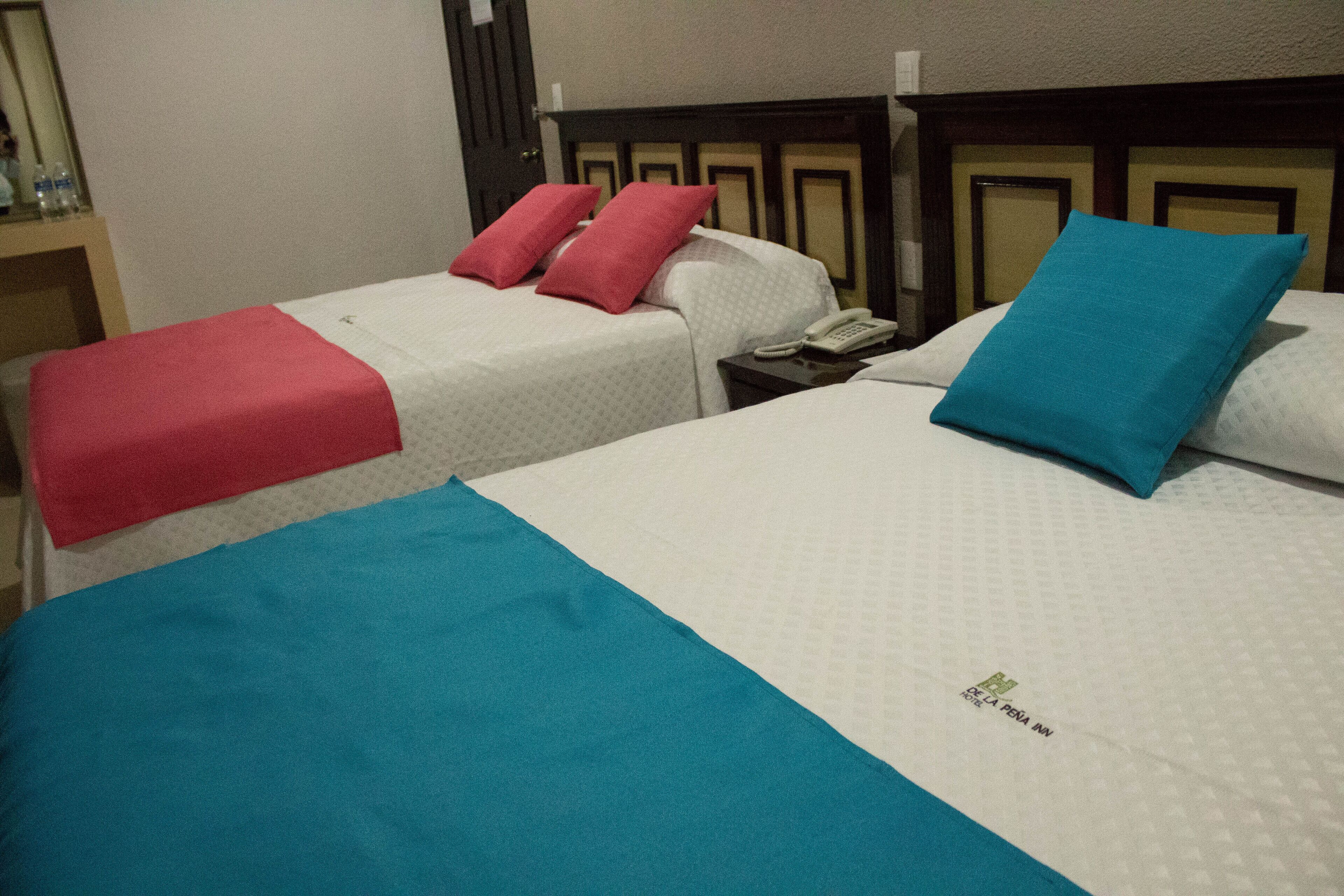 A hotel room with two beds, each with a different colored blanket and pillow.
