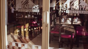 Un restaurant dont le sol est recouvert d’un motif à carreaux et qui possède une porte en verre ornée d’un logo.