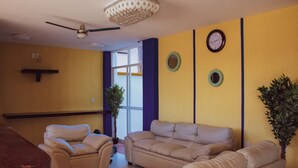 Un salon avec des canapés de couleur beige, un ventilateur de plafond et une grande fenêtre.