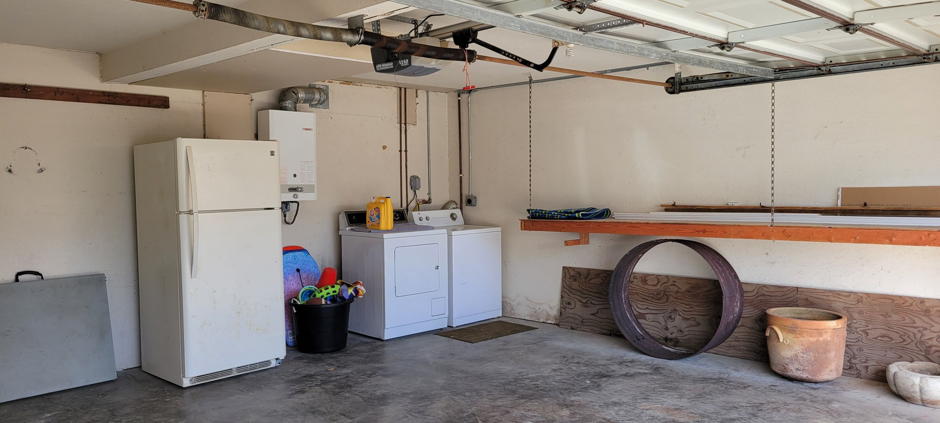 A utility room with a refrigerator, washing machine, and a water heater.