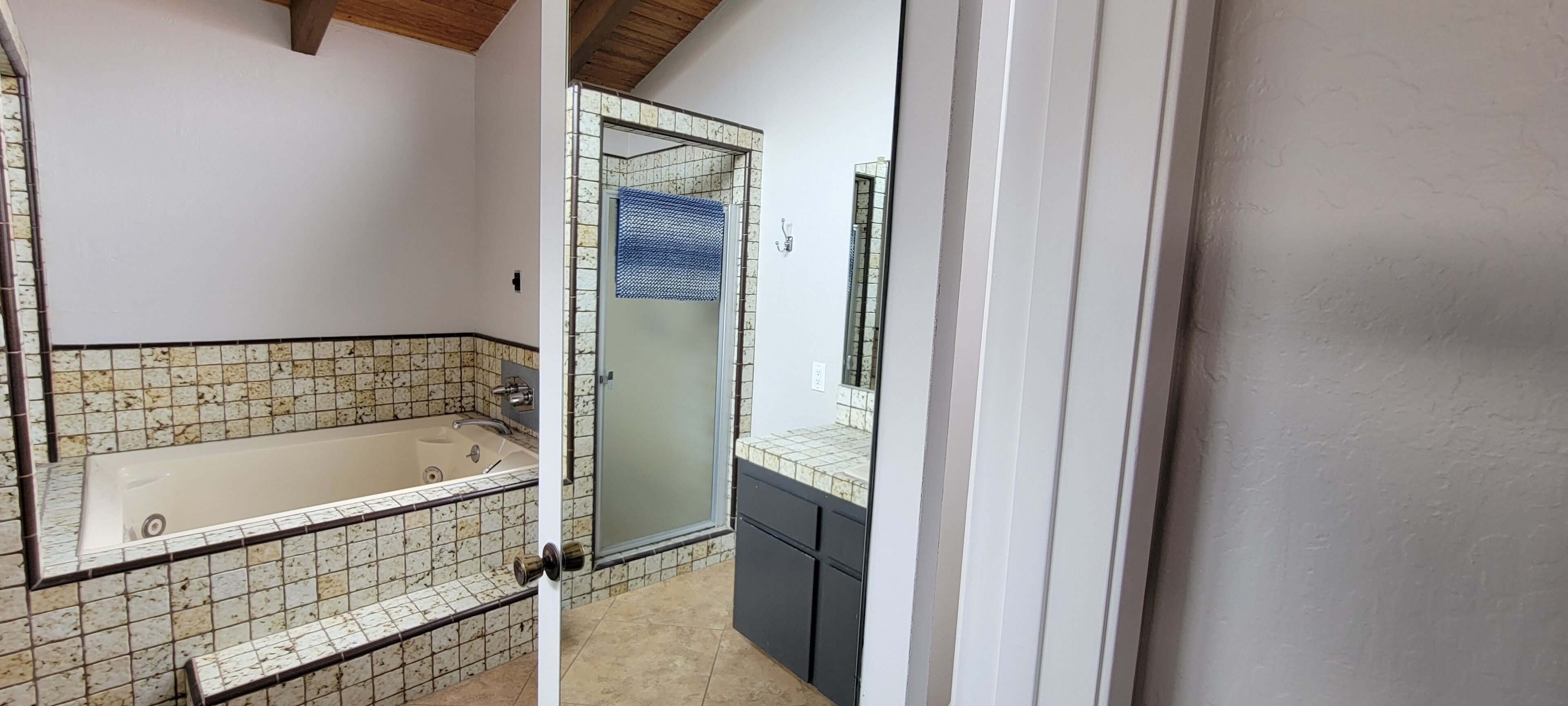 A bathroom with a bathtub, a glass shower enclosure, and tiled walls.