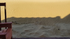 A beach scene with a wooden deck and a white post in the distance.
