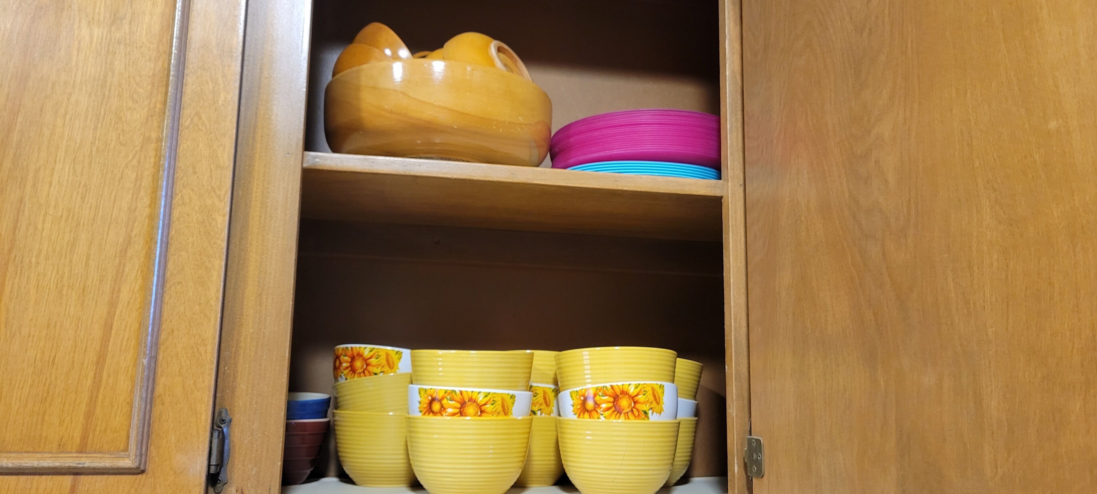 A wooden cabinet with shelves holding various bowls and plates.