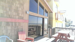 A building with a wooden exterior, a glass door, and a balcony with picnic tables.