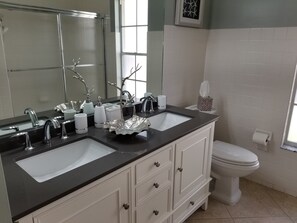 A bathroom with two sinks, a mirror, a toilet, and a window. - Crown Pointe Home with Lake Views! (Naples)