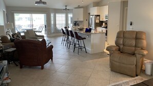 A spacious living area with a kitchen, dining area, and a large window providing natural light. - Crown Pointe Home with Lake Views! (Naples)