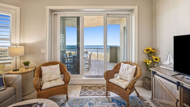 A room with two wicker chairs, a TV, and a view of the beach through a sliding glass door. - Ocean Place Resort~incredible views and oversized balcony (Fernandina Beach)