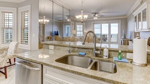 A kitchen with a large island, stainless steel sink, and a chandelier. - Ocean Place Resort~incredible views and oversized balcony (Fernandina Beach)