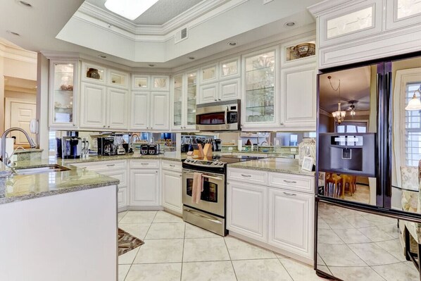 Enjoy cooking in this well-equipped kitchen with a large island, stainless steel appliances, and a refrigerator.
