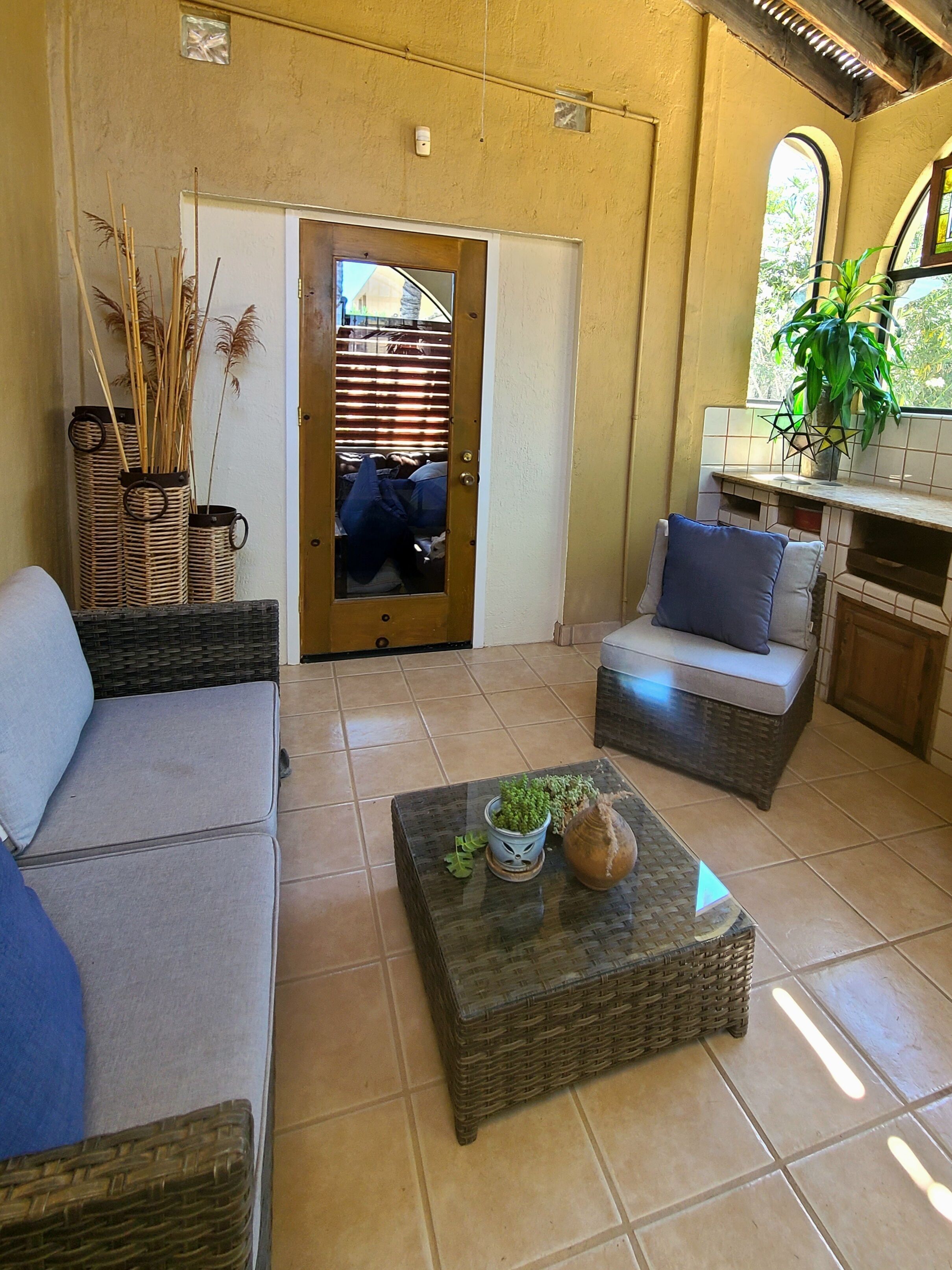A cozy living area with a sofa, a coffee table with plants, and a wicker chair.