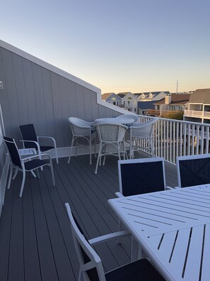 A deck with white wicker furniture and a white table, overlooking a residential area with houses. - Oceanblock, steps to best beach in Bethany (Bethany Beach)