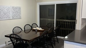 A dining area with a wooden table and chairs, a ceiling fan, and a sliding glass door leading to an outdoor deck. - Oceanblock,  steps to best beach in Bethany (Bethany Beach)