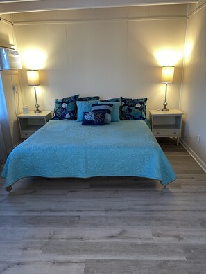 A bedroom with a large bed, two bedside tables with lamps, and a wooden floor. - Oceanblock, steps to best beach in Bethany (Bethany Beach)