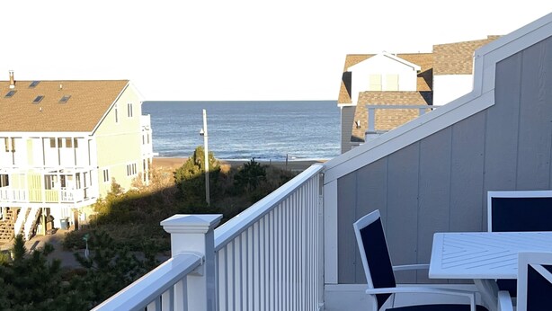 A balcony with a view of the ocean, white wicker furniture, and a railing. - Oceanblock,  steps to best beach in Bethany (Bethany Beach)