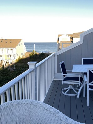 A balcony with a view of the ocean, white wicker furniture, and a railing. - Oceanblock, steps to best beach in Bethany (Bethany Beach)
