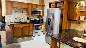 Una cucina moderna con mobili in legno, elettrodomestici in acciaio inossidabile e un piano di lavoro in granito.