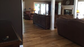 A spacious living room with a fireplace, wooden flooring, and brown sofas.