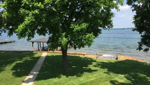 A grassy area with a wooden deck and a gazebo by a lake.